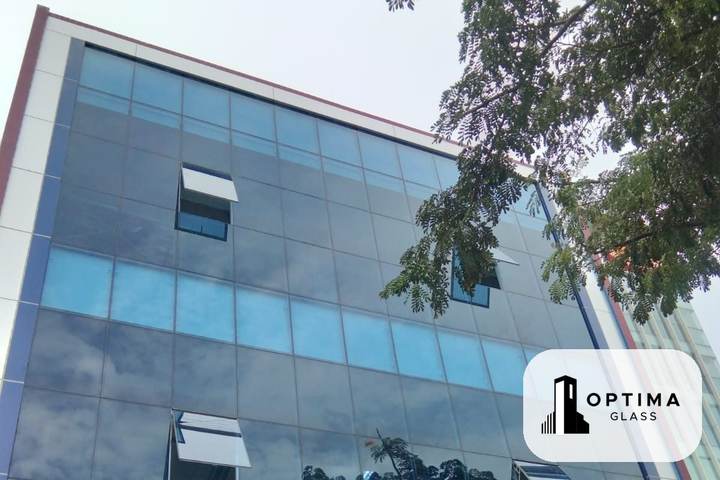 Fasad curtain wall kaca biru pada gedung bertingkat