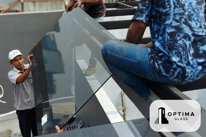 Dua tukang kaca mengangkat panel kaca tempered ke atas rangka kanopi di lantai atas