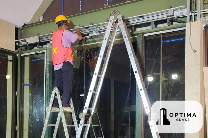 Tukang memasang dinding kaca frameless tinggi dengan fitting di bagian atas