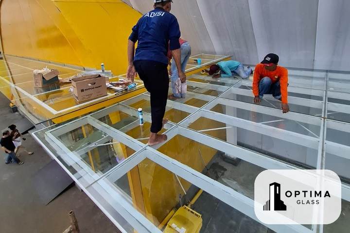 Tukang memasang kaca atap skylight di atas rangka pada sebuah gedung