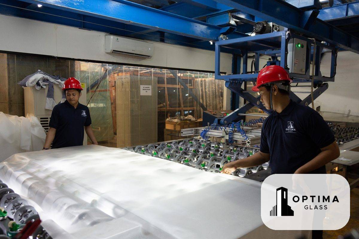 Dua staf Optima Glass menyiapkan film PVB di atas kaca pada lini laminasi pabrik Cikarang
